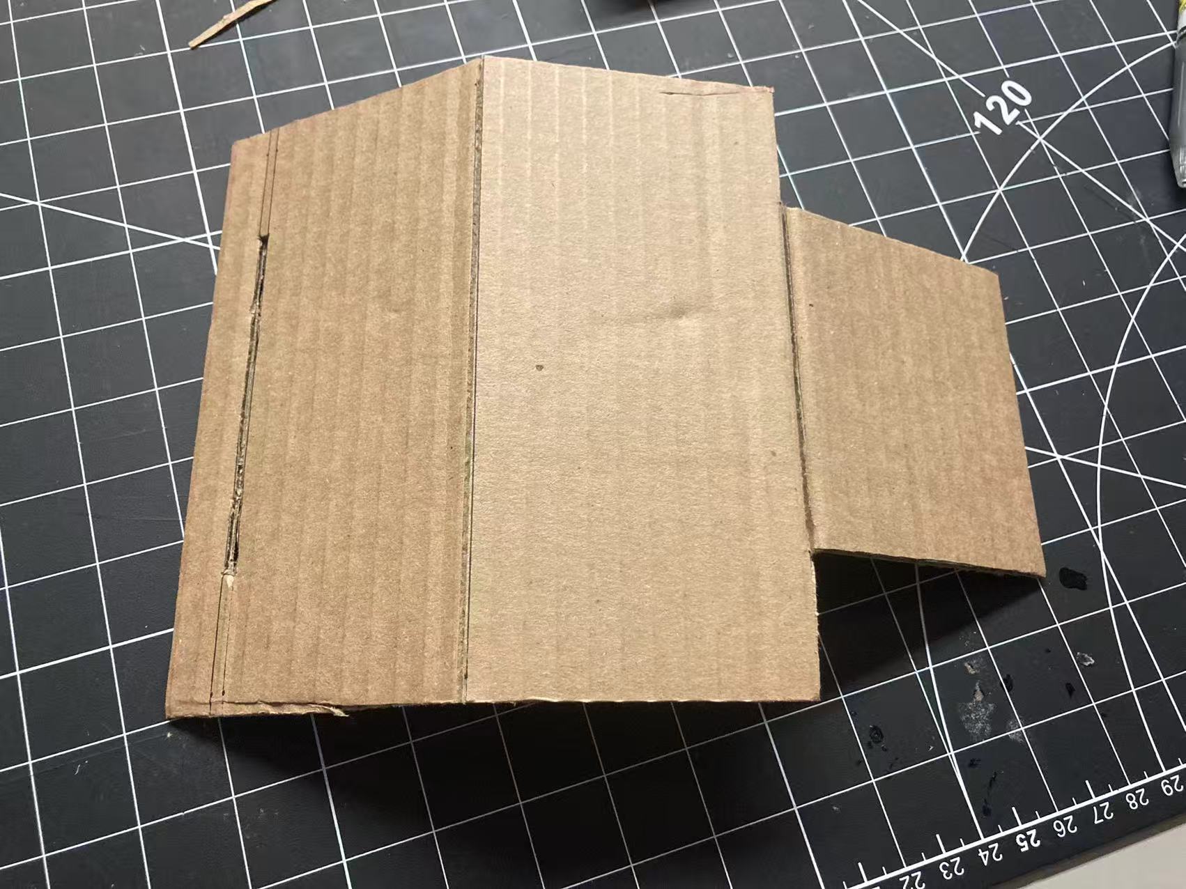 Fold the cardboard along the marked lines to curve and insert it, forming the front tabletop to complete the assembly.